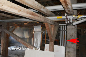 Die Hauptleitungen verlaufen durch das unbeheizte Dachgeschoss. Von dort zweigen Leitungen zu den Wohnungen ab; das Bild zeigt beispielhaft einen solchen Abzweig (Pfeil).