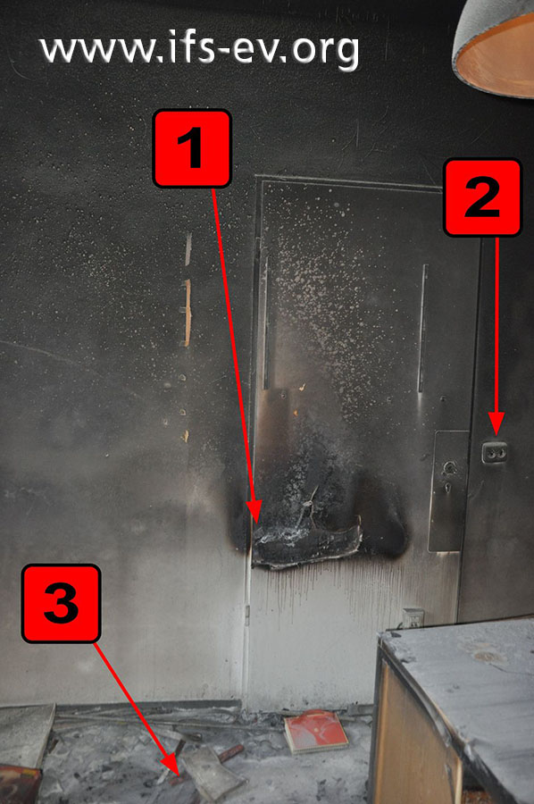 Der Brandraum: An der Tür gibt es eine auffällige Brandsprur (1). Pfeil 2 markiert die Steckdosen und Pfeil 3 eine Packung Wunderkerzen.