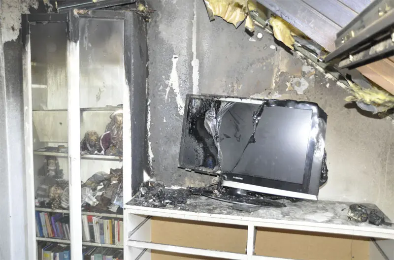 Zwischen Fernseher und Vitrine zeichnet sich ein Brandtrichter ab.