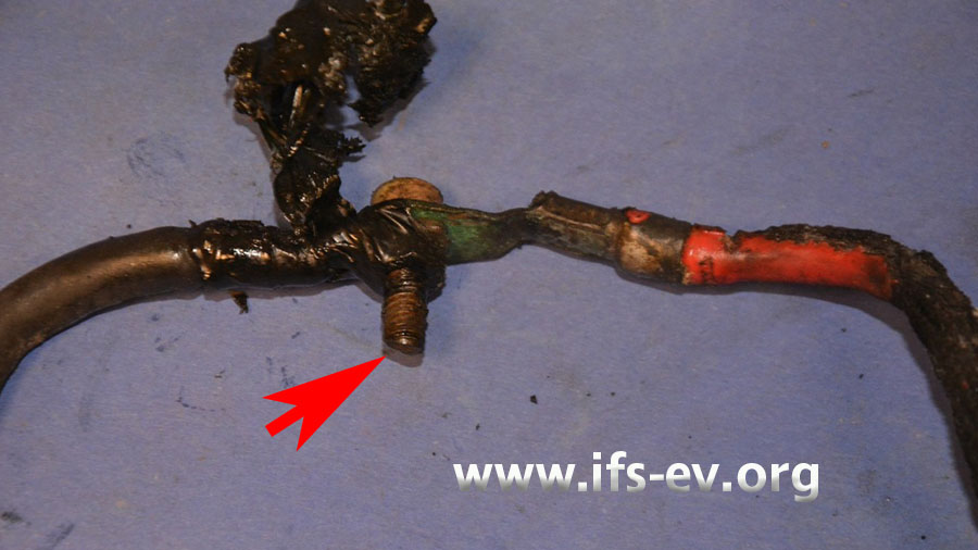 Im Brandschwerpunkt wurden zwei Leitungen mit Kabelösen und einer Schraube verbunden. Der Pfeil markiert Schmelzspuren an der Schraube.