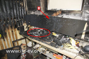 Die Brandzehrungen am Regalbrett (1), das über der Werkbank angebracht war, sind ein Hinweis darauf, wo das Feuer entstanden ist.