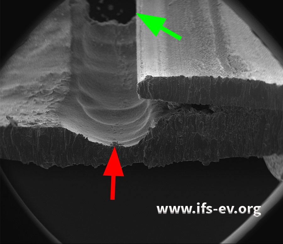 Die elektronenmikroskopische Ansicht des Materialabtrags auf der Röhrcheninnenseite (roter Pfeil) im Bereich des Loches (grüner Pfeil)