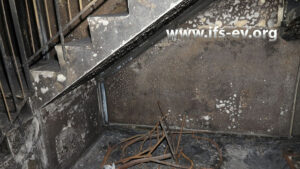 Reste eines verbrannten Kinderwagens unter der Treppe im Erdgeschoss