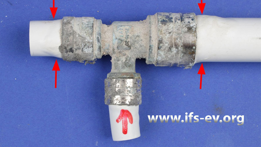 Das T-Stück mit der Undichtigkeit an der markierten Verbindung: Die Rohre sind im Bereich der Druckhülsen aufgequollen (Pfeile).