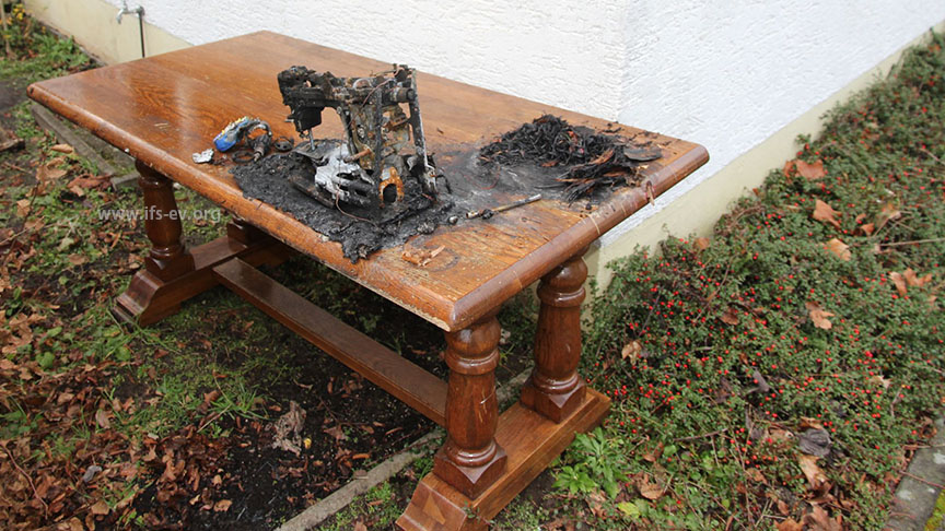 Der Tisch wurde von der Feuerwehr nach draußen gebracht. Unser Gutachter rekonstruierte anhand der Einbrennungen auf der Tischplatte, wo die Nähmaschine und der Adventskranz standen.