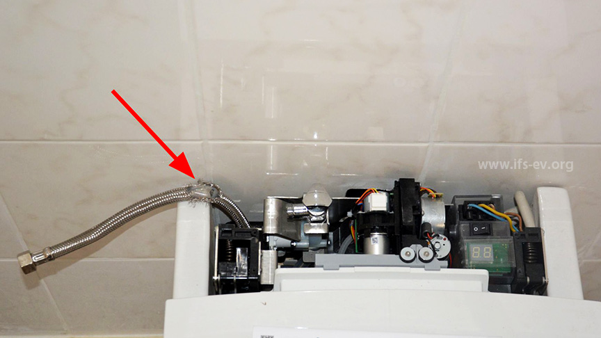 Im hinteren Bereich des Dusch-WC befindet sich die Steuerungstechnik. Der beschädigte Schlauch hängt heraus (Pfeil).