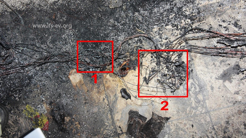 Die Überreste der Verteilerdose für die Kühlgeräteanschlüsse (1) und der Doppelsteckdosenleiste (2), an die die brandbetroffene Kühltruhe angeschlossen war.